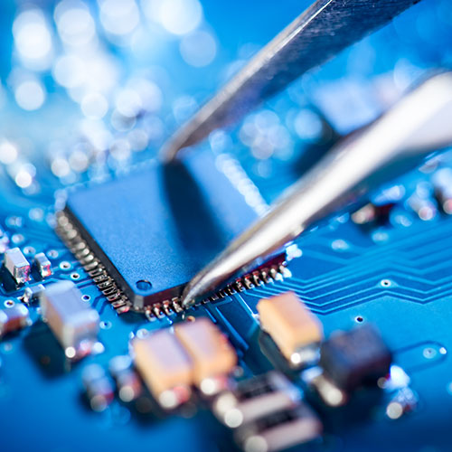 Electronic technician holding tweezers and assembling a circuit board